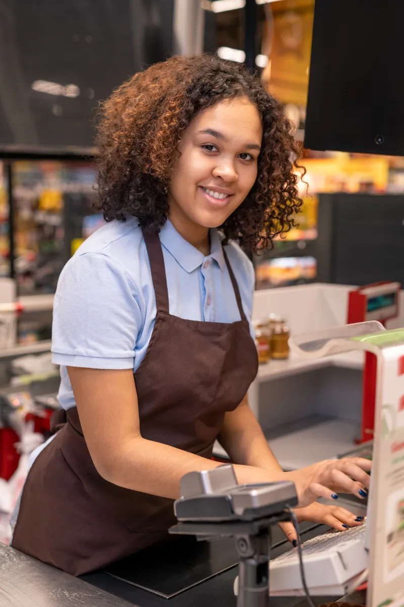Cashier smiling at the register during a store shift