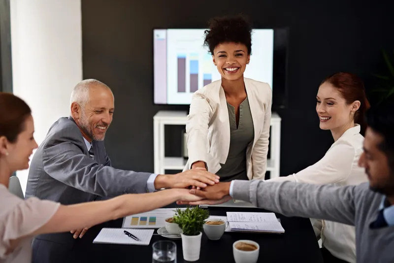 Sales team with hands in over the conference table