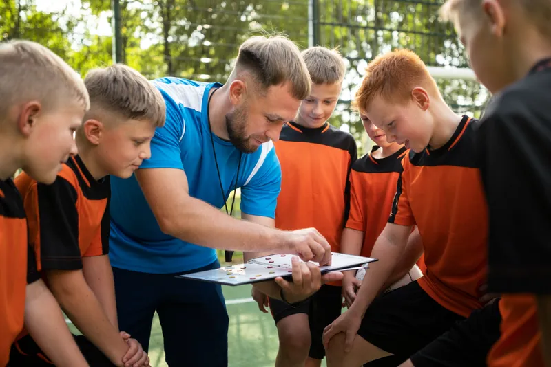 Coach walking a youth team through a play on a tactics board