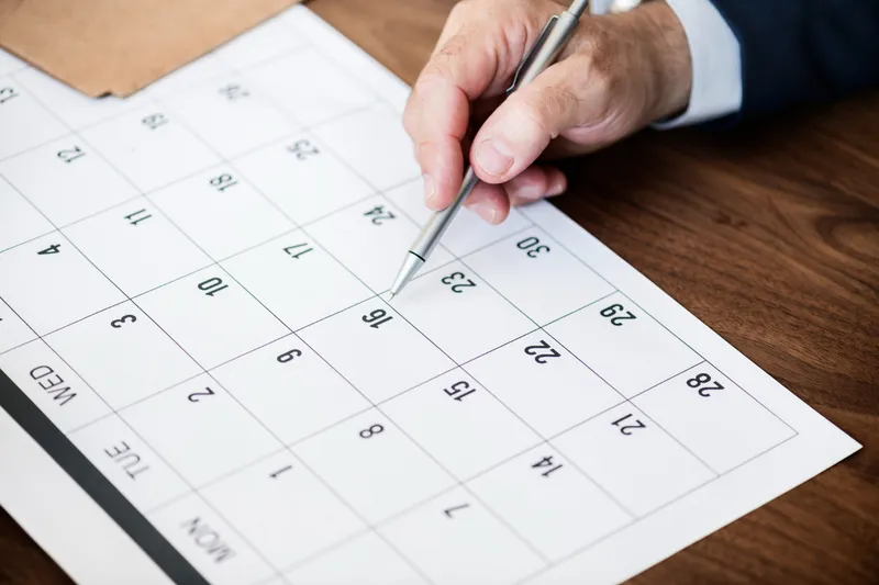 Hand marking dates on a paper calendar