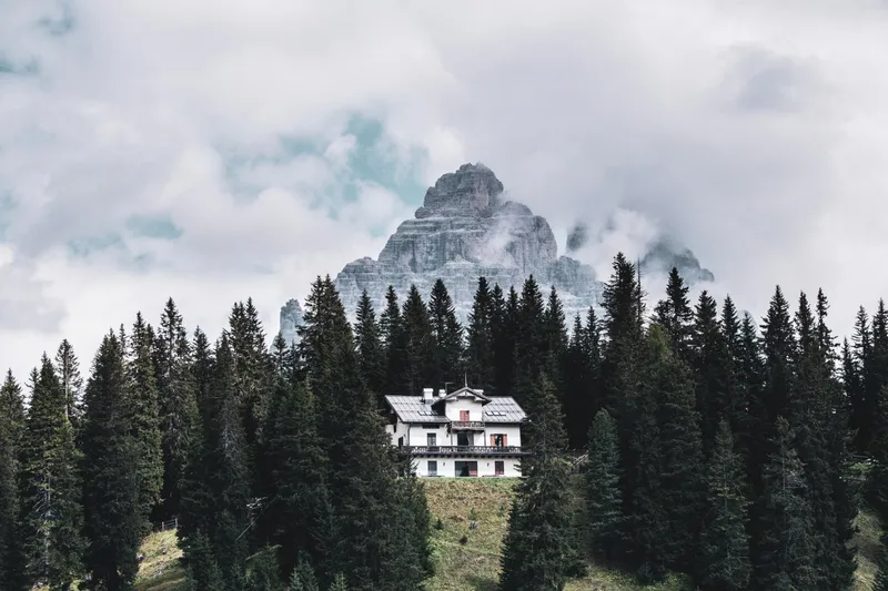 Mountain chalet surrounded by pines below a rocky peak