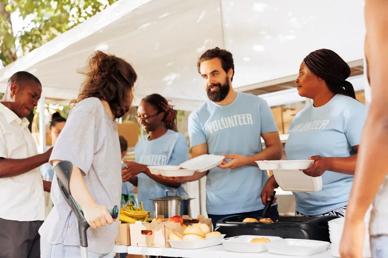 Volunteers in matching shirts serving food at an event booth